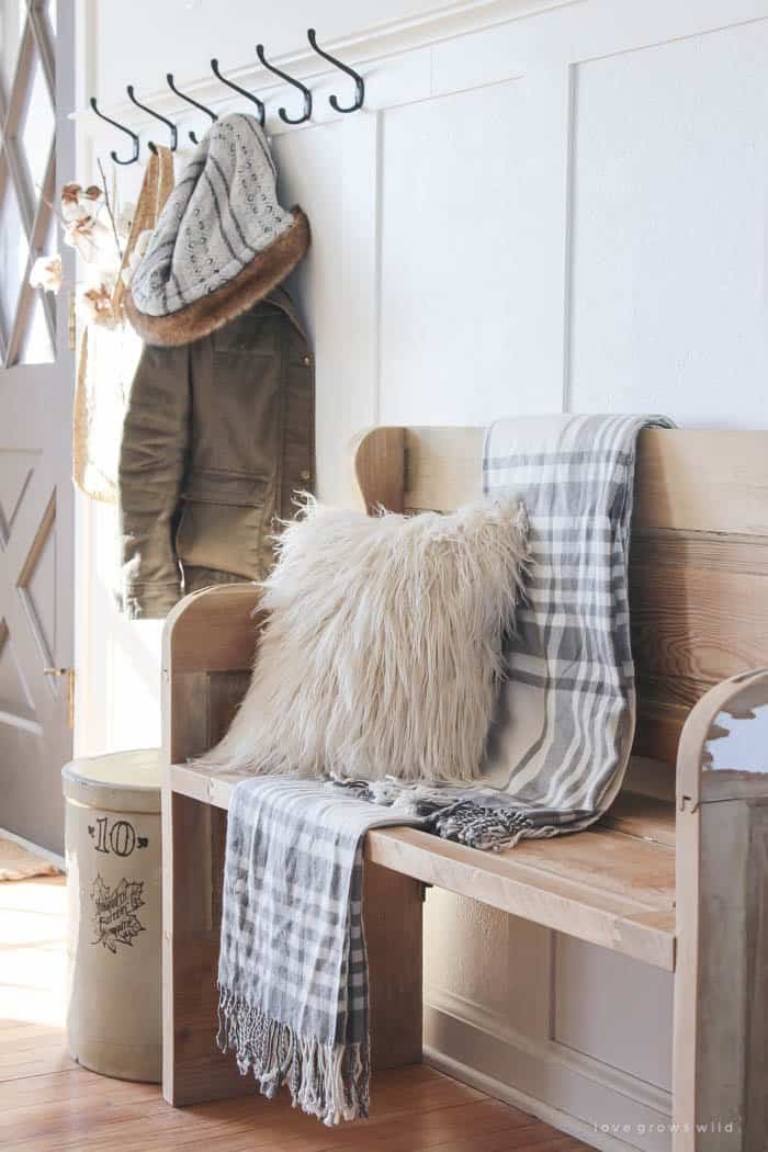 Farmhouse winter entryway with wood bench and coat hooks