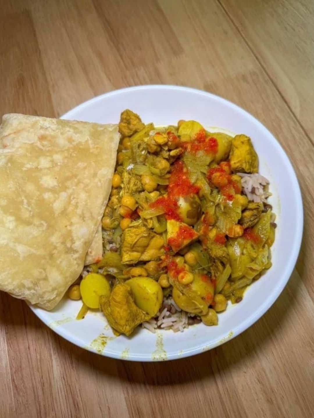 Curry chicken with chickpeas and potatoes over rice, served with roti