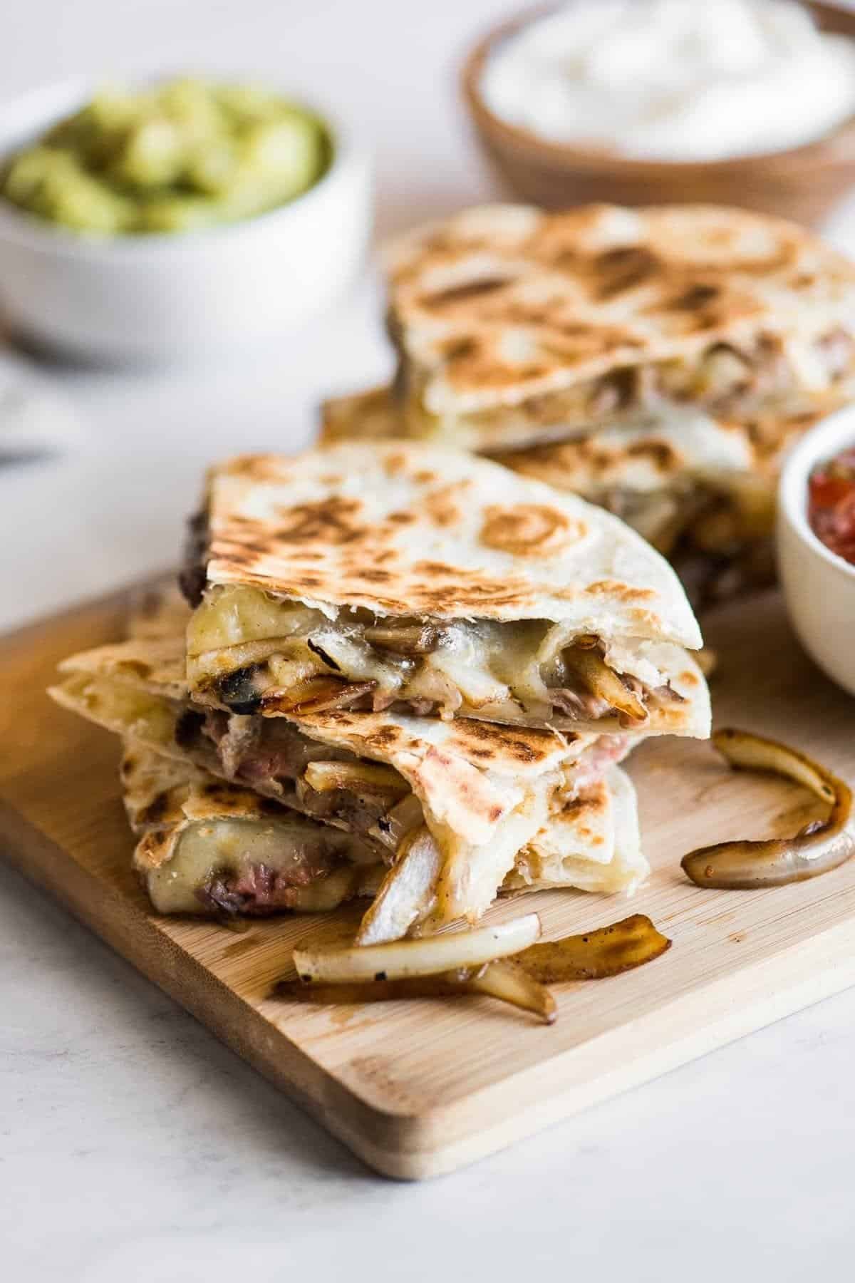 Steak quesadillas with melted cheese and onions on a board