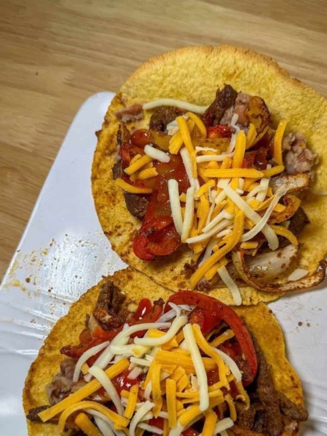 Steak fajitas with bell peppers, onions and shredded cheese on tortillas