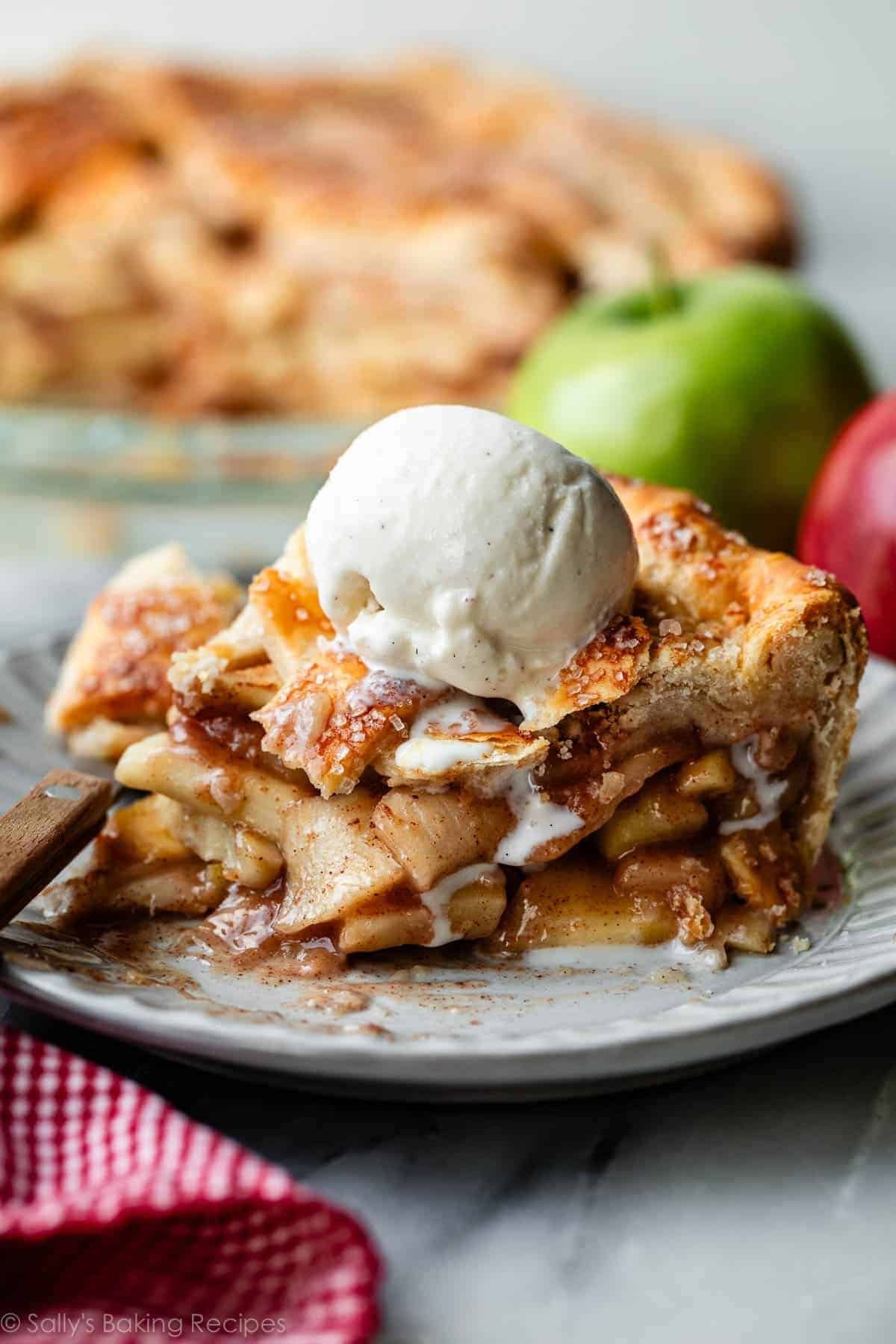 Slice of classic homemade apple pie with a flaky crust and vanilla ice cream