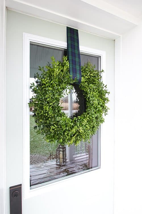 Blue and white Christmas porch with a boxwood wreath on a white door