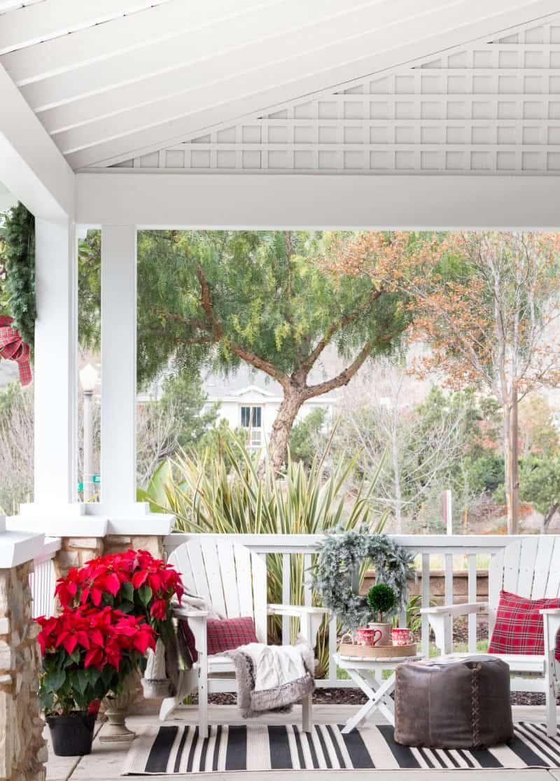 Christmas front porch with red and black plaid blankets, poinsettias and a frosted wreath