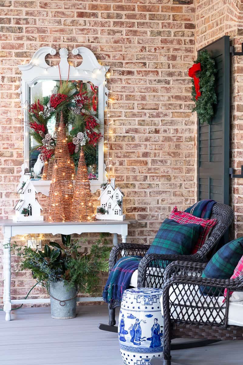 Southern Christmas porch with a white console, glowing lights and a wreath on the door