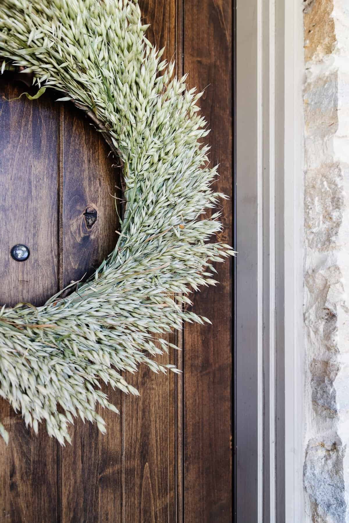 Simple DIY dried oat and grass wreath on a grapevine form hanging on a front door