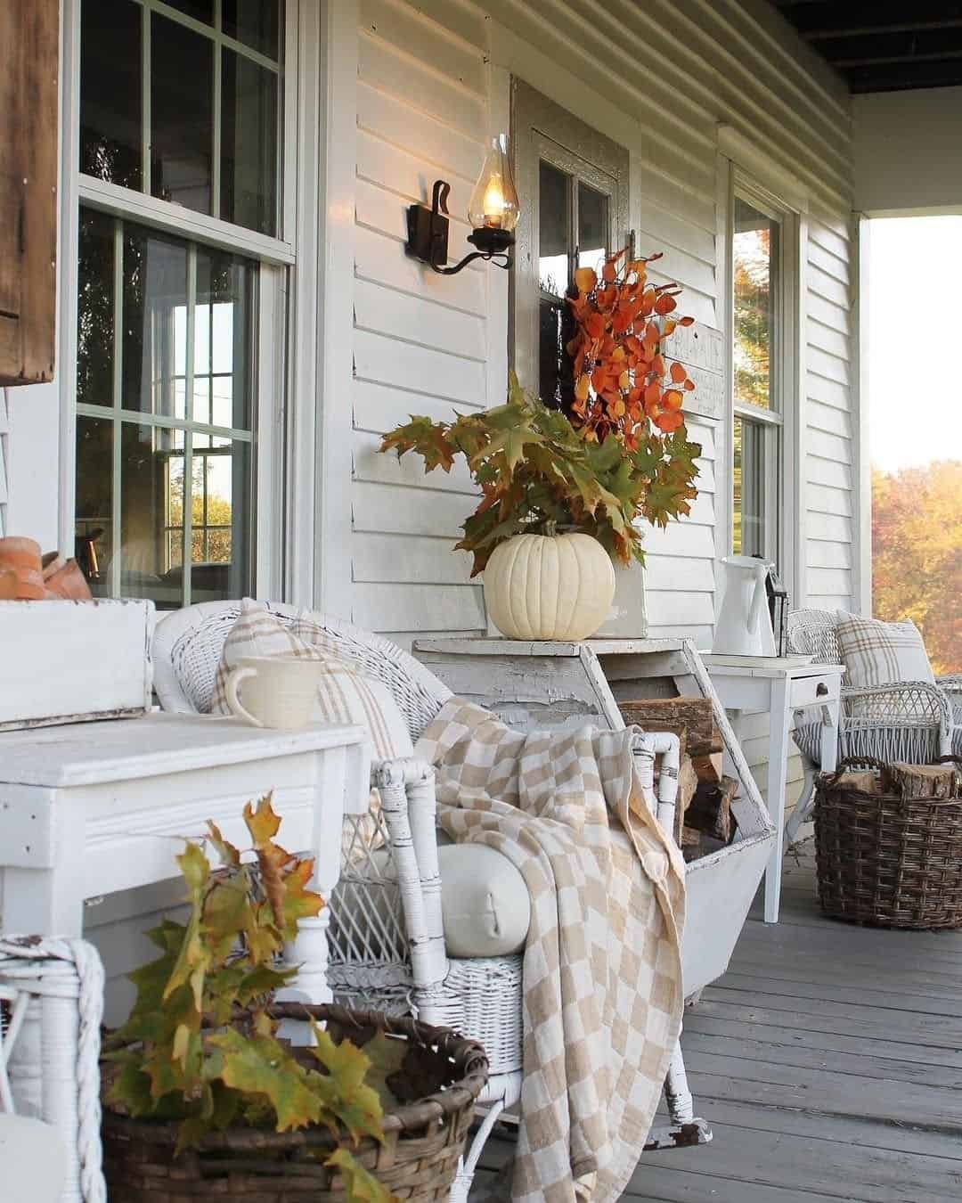 Narrow porch layered with plaid throws, woven baskets and distressed white furniture in a neutral palette