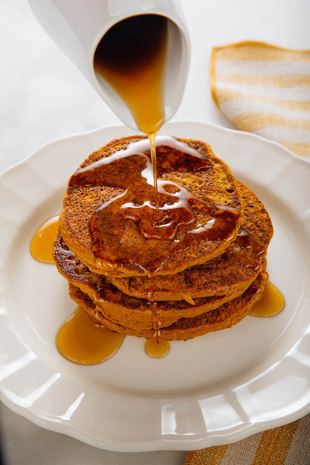 Stack of pumpkin oat pancakes with maple syrup