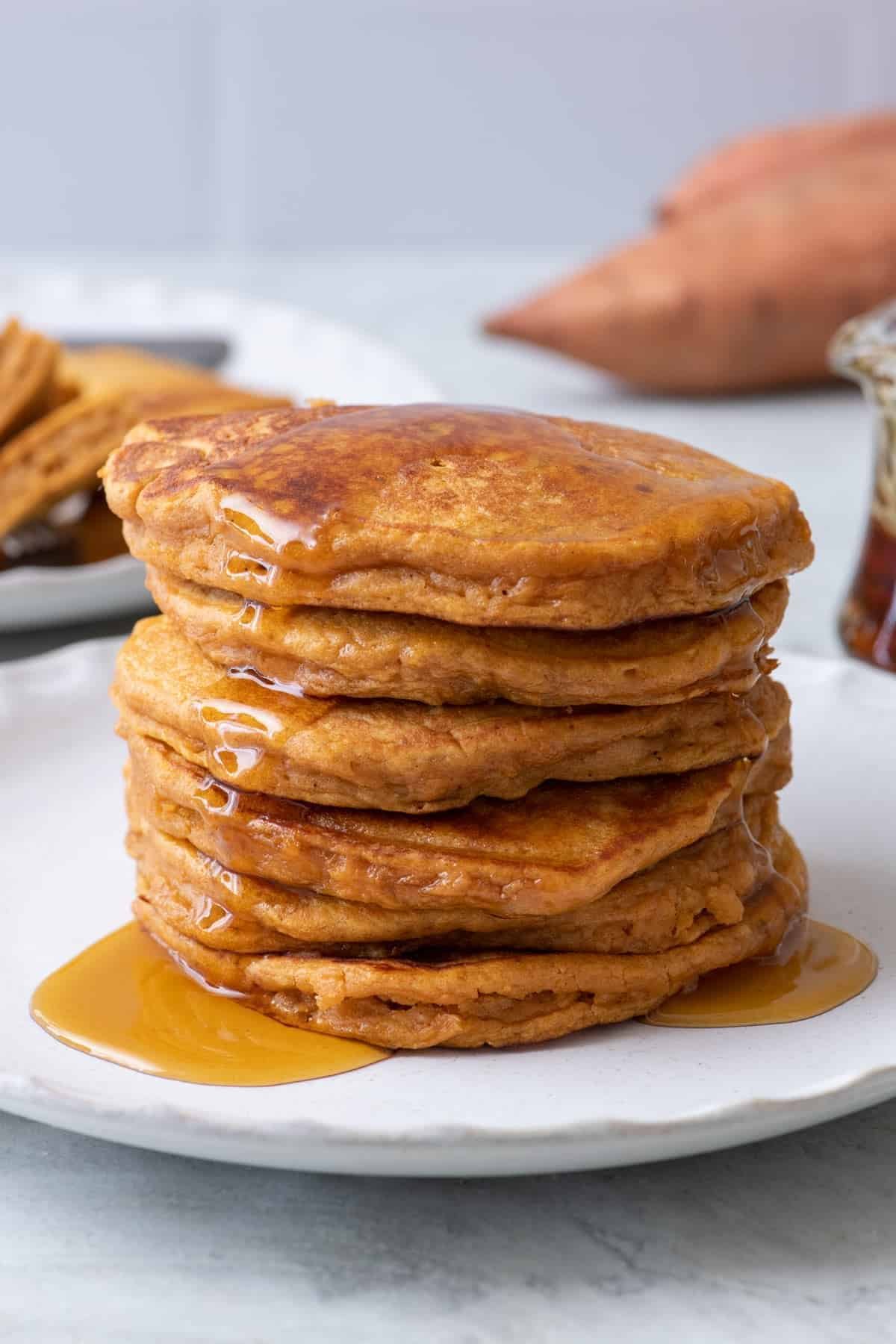 Stack of fluffy sweet potato pancakes with maple syrup