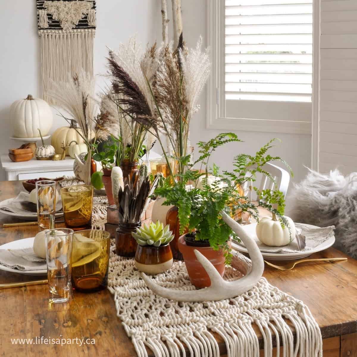 Boho Thanksgiving table with a macrame runner, pampas grass, potted plants and henna style pumpkins