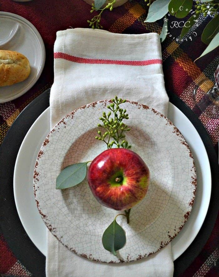 Budget Thanksgiving table with a plaid scarf runner, hydrangeas in a copper bowl and apples on each plate