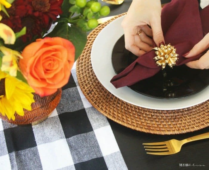 Buffalo plaid Thanksgiving table with rattan chargers, black salad plates and burgundy napkins