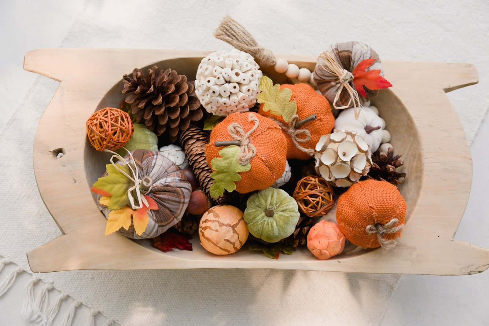 Vintage dough bowl filled with pinecones, acorns, velvet pumpkins and a wood bead garland