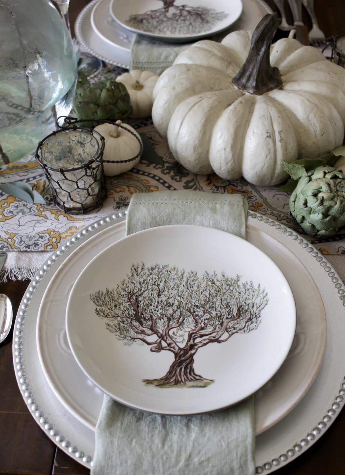 Elegant fall table with a green patterned runner, sage napkins, white pumpkins and eucalyptus
