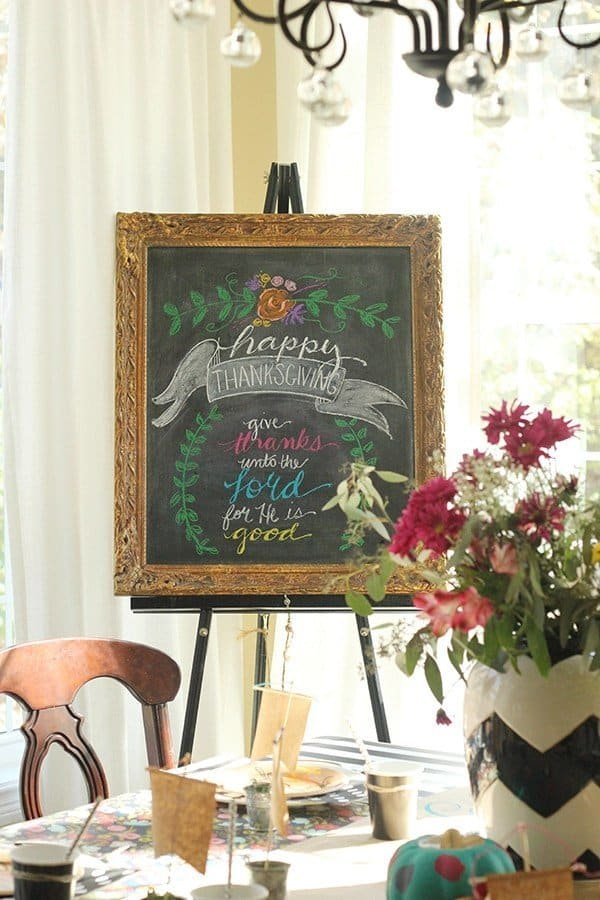 Colorful kids Thanksgiving table with a floral wrapping paper tablecloth and a chalkboard