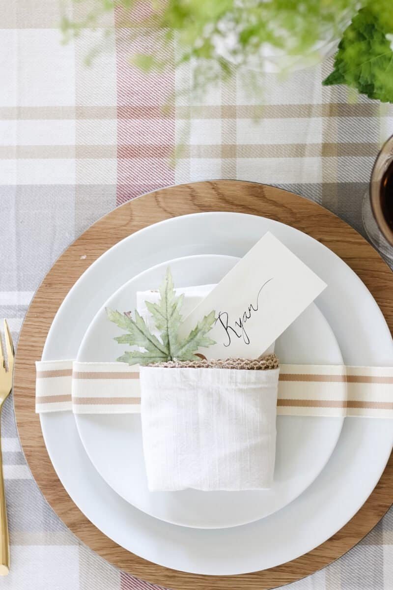 Plaid Thanksgiving table with wood chargers, gold flatware and napkins folded into pockets