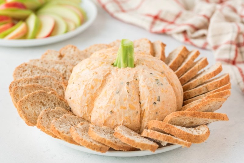 Pumpkin shaped cheddar cheese ball with crackers and apple slices