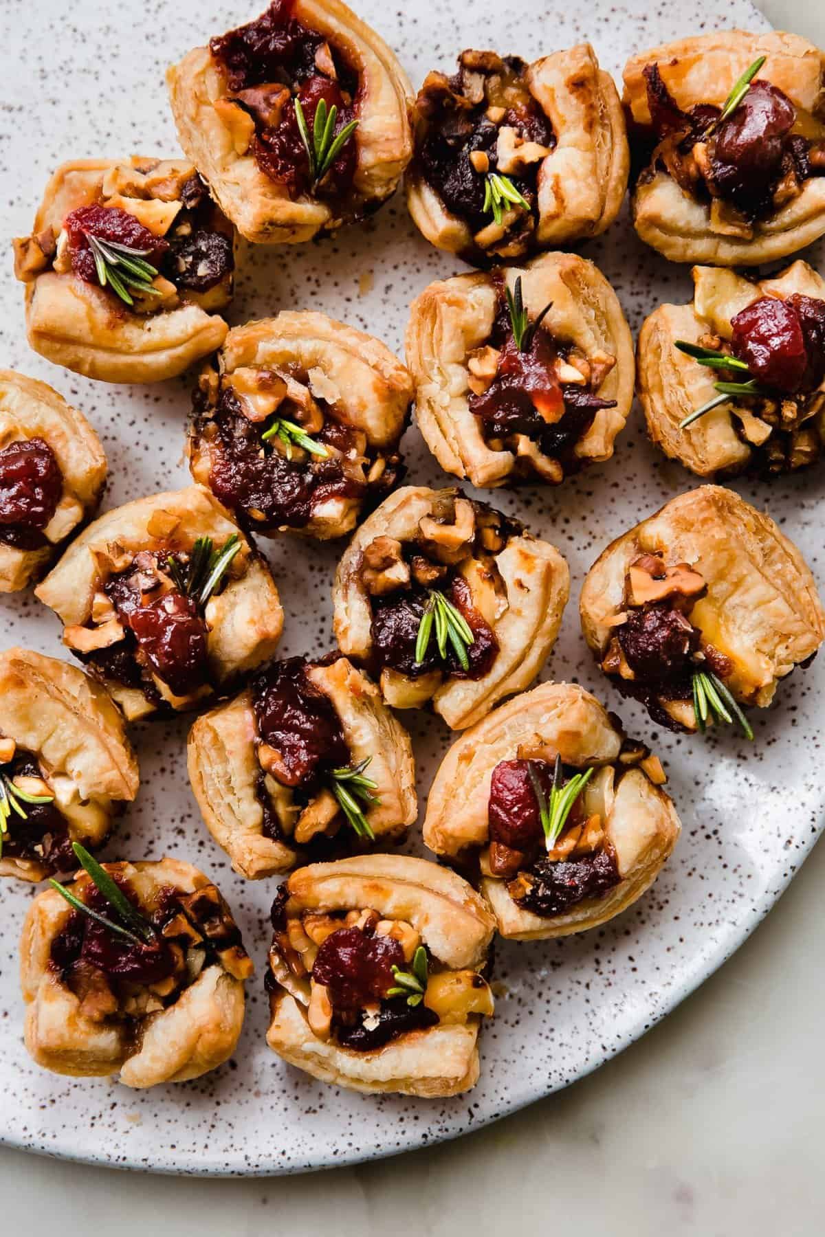 Puff pastry cranberry brie bites topped with walnuts and rosemary