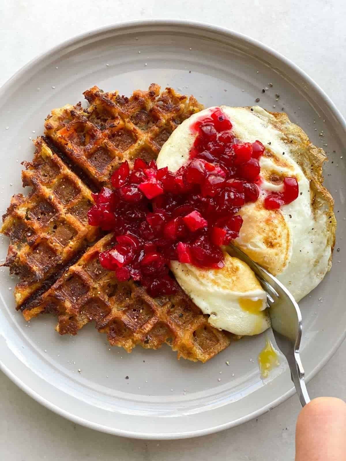 Crispy leftover stuffing waffles topped with a fried egg and cranberry sauce